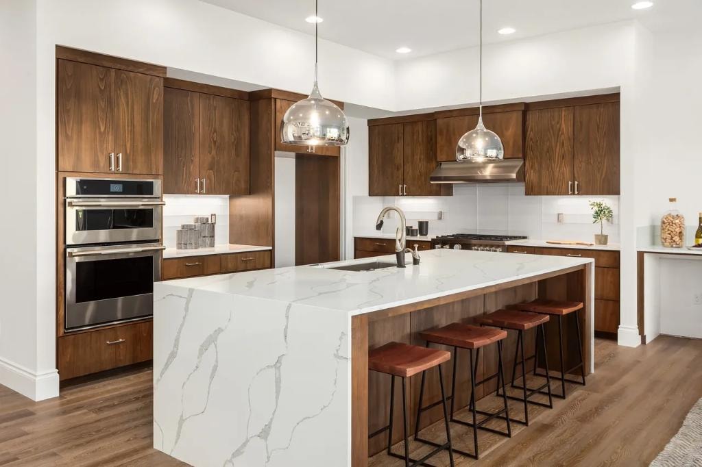 Modern kitchen with dark walnut cabinets, marble island, and pendant lights