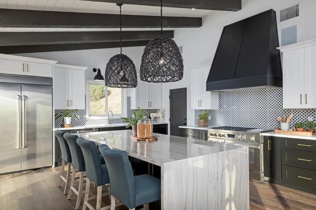 Dramatic kitchen with dark cabinetry, woven pendant lights, and marble island