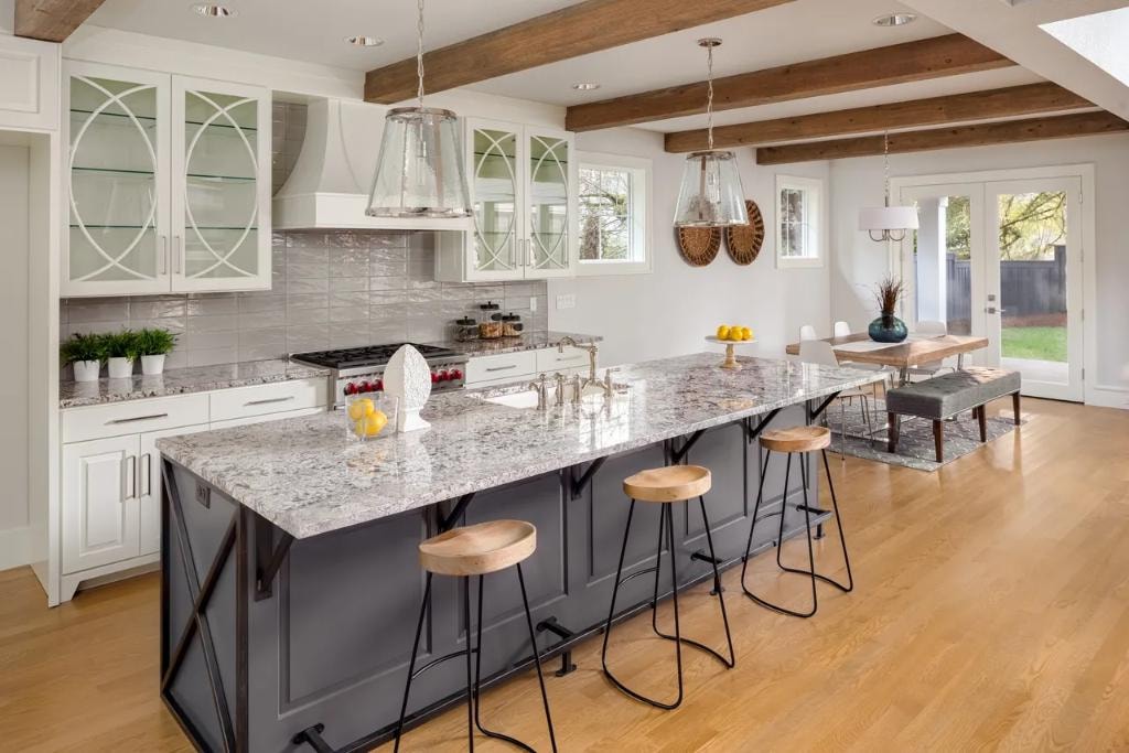 Bright kitchen with glass-front cabinets, granite island, and exposed wood beams